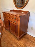 Front view showing hinged flip-front top, drawer above two-door cabinet