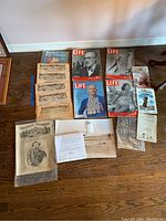 Collection of vintage magazines and ephemera spread on wooden floor, includes Life magazines, Sports Illustrated, Harper's Weekly issues, and Ballou's Pictorial