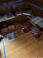 Two wooden bookshelves corner view showing numerous Lehigh Valley history books, some stacked on the floor, with three bricks placed near the bottom shelf.