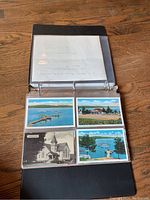 Open black 3-ring album displaying four postcards depicting waterfront and dock scenes, a church, and rural buildings in the Lehigh Valley area.