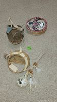 Four handcrafted Native American items including woven baskets and decorated antler pieces laid on carpet.