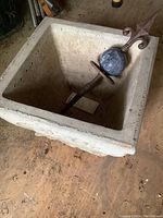 Inside view of cement planter containing heavy metal stake with dark stone-like spherical ball and fleur-de-lis metal top.