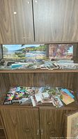 Display of multiple color postcards with scenic natural views including water and trees on a wood shelf