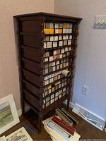 Front side view of the 7-tier wooden shelving unit containing many small boxes and some scattered items on the floor around it.