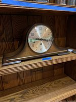 Front view of the Linden tambour mantle clock showing the full wooden curved case, silver dial with black numerals, and decorative clock hands.