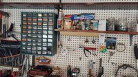Full view of pegboard with multi-drawer organizer, shelves with jars and boxes, hand tools, and hanging hardware.