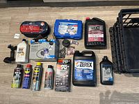 Overview of automotive liquids, toolkits, jump starter wires, and storage crates laid out on floor.
