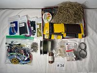 Top view of assorted jewellery making materials including cords, tassels, chains, and metal findings spread out on white background.