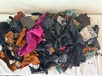Top view of large assorted pile of leather scraps in multiple colors including pink, black, brown, tan, and teal.