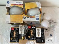 Wide view of all 9 bulbs including boxed large GE bulbs, 2 white medium bulbs, and 4 boxed Globe vintage bulbs with halogen bulb loose.