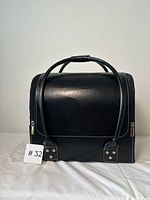 Front view of black makeup case with carry handle showing material texture and stitching.