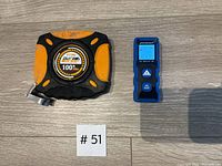 Front view of 100 ft tape measure showing rubber grip and label, alongside blue Mastercraft laser distance meter with display and buttons visible.