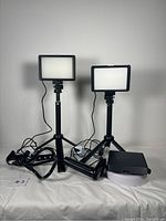 Two LED panel lamps on adjustable tripods with power cables and a black box for lens kit.
