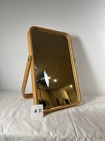 Front angled view of wooden framed standing mirror showing reflective surface and curved frame edges.