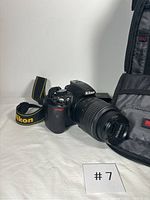 Nikon D3100 camera with lens, Nikon strap, and partially opened camera bag visible