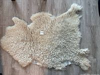 Top side view of natural sheepskin rug showing creamy beige, curly wool texture and organic shape