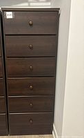 Front view of the tall dresser showing six drawers with round knobs, one knob missing.