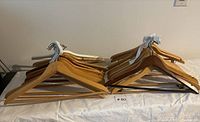Two stacks of wooden hangers on a white surface, some with metal bars and some with shoulder notches.