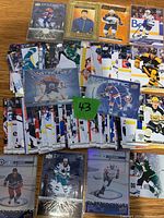 Top-down view of a large pile of hockey cards from Upper Deck Series 2 2023-24 season including base cards and special inserts with a green note numbered 43
