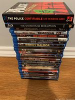 Stack of 23 Blu-Ray plastic cases with titles visible on the spines, showing a mix of movie genres and some foreign versions.