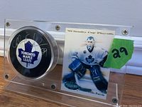 Clear acrylic display stand showing autographed Toronto Maple Leafs puck and Felix Potvin hockey card
