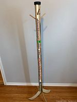 Full view of the hockey stick coat hanger showing the base made from curved blade ends and four wooden pegs near the top.