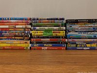 Front view of a stacked lot of kids DVDs showing visible spines including Disney and other animated films.