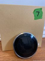 Front view of the Nest Learning Thermostat against a cardboard box