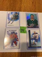 Four NHL rookie cards laid out on a table with each card sleeved. Cards shown are Sasha Chmelevski (top left), Jason Robertson (top right), Cole Caufield (bottom left), and Jake Quinn (bottom right). A green label marked 39 is visible between the cards.