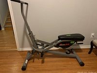Full view of the gray Power Glide exercise machine showing seat, handlebars, and base supports.