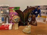 Photo showing the full lot including Toronto Blue Jays baseball on stand, Master Lock box, billiard accessory pack, leaf-shaped ceramic vase, wooden carved bust, alabaster chess knight, and magnetic memo holder with miniature bottles