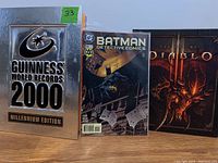 Front view of three books: Guinness World Records 2000, Batman Detective Comics #664, and The Art of Diablo 3 art book
