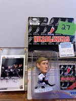 Photo showing Wayne Gretzky bobblehead figure sealed in NHLPA Headliners packaging with NHLPA and Irwin branding, alongside Gretzky hockey card in a protective plastic case.