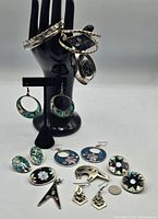 Photo shows entire lot: multiple pairs of earrings, bracelets on black hand display, assorted abalone shell and metal jewelry pieces.