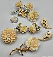 Five bone and rhinestone jewelry pieces including three brooches - large floral with enamel, smaller floral with rhinestones, round flower brooch; and two pairs of carved bone earrings - paisley-shaped pierced and rose studs.