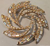 Front view of vintage rhinestone brooch showing swirl pattern and rhinestones.