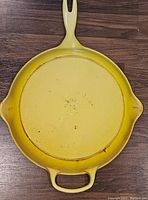 Bottom view of yellow enamel Le Creuset pan showing yellow enamel with some wear marks and '30' mark in center.