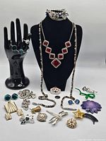 Full lot of mixed costume jewelry, including Butler signed red necklace, bracelets, rings, brooches, pins, and a green snake brooch with dime for size reference.
