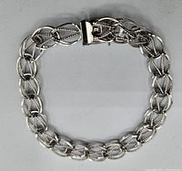 Full view of the sterling silver chain bracelet laid flat in a circular shape, showing the design and clasp.