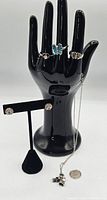 Full lot displayed on black hand model and earring stand, showing three rings on hand and earrings on stand with pendant chain hanging.