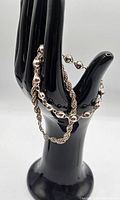Two sterling silver bracelets on a black hand-shaped stand showing chain styles and overall condition.