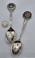 Two sterling silver enamel spoons side by side with quarter for scale