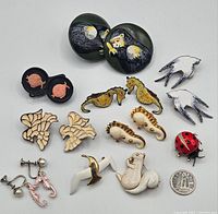 Overview photo of lot showing all seven pairs of earrings and three pins arranged on white background for condition and design detail review.