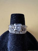 Front view of engagement ring stacked on wedding band on black display