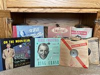Display of multiple 78 RPM record covers and sleeves on a shelf, including Bing Crosby Christmas album and Vaughn Monroe record.