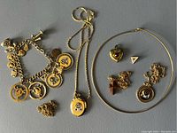 Full spread of the jewelry lot showing charm bracelet, two necklaces with pendants, pair of earrings, and several small charms.