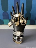 Photo of multiple ladies wristwatches displayed on a black hand display, showing various styles and metal bands.