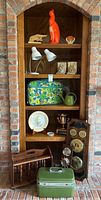 Wide view of wooden bookshelf with various mid century decorative items including luggage, ceramic cat, clocks, lamps, and more.