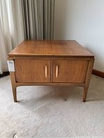 Front view of walnut side table with twin cabinet doors and wood handles