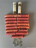 Full lot view showing various wrapped rolls of pennies and two tubes with steel pennies, plus loose coins below.